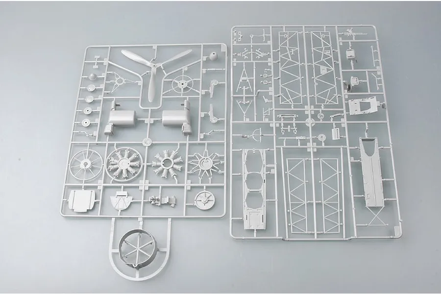 Two grey plastic model kit sprues containing various aircraft parts including a propeller, engine components, and structural frames.