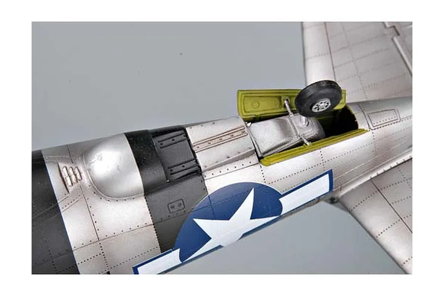 Close-up of a P-47 Thunderbolt model aircraft showing the silver fuselage, landing gear bay, and US military insignia.