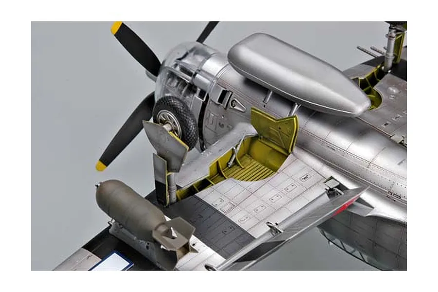 A detailed scale model of a P-47 Thunderbolt aircraft, showing the landing gear bay, under-wing bomb, and silver fuselage finish.