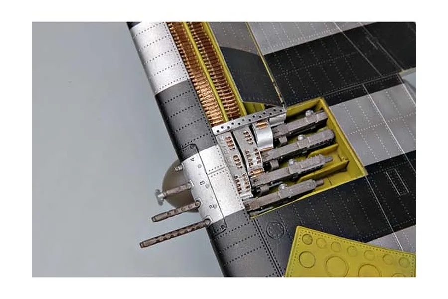 Close-up of a P-47 Thunderbolt model aircraft wing with the gun bay open, showing machine guns and ammunition belts.