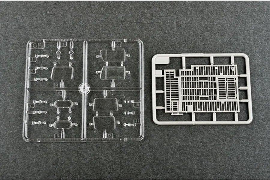 Two plastic model kit sprues on a dark grey background, one clear plastic sprue with windows and one grey plastic sprue with a grid-like structure.