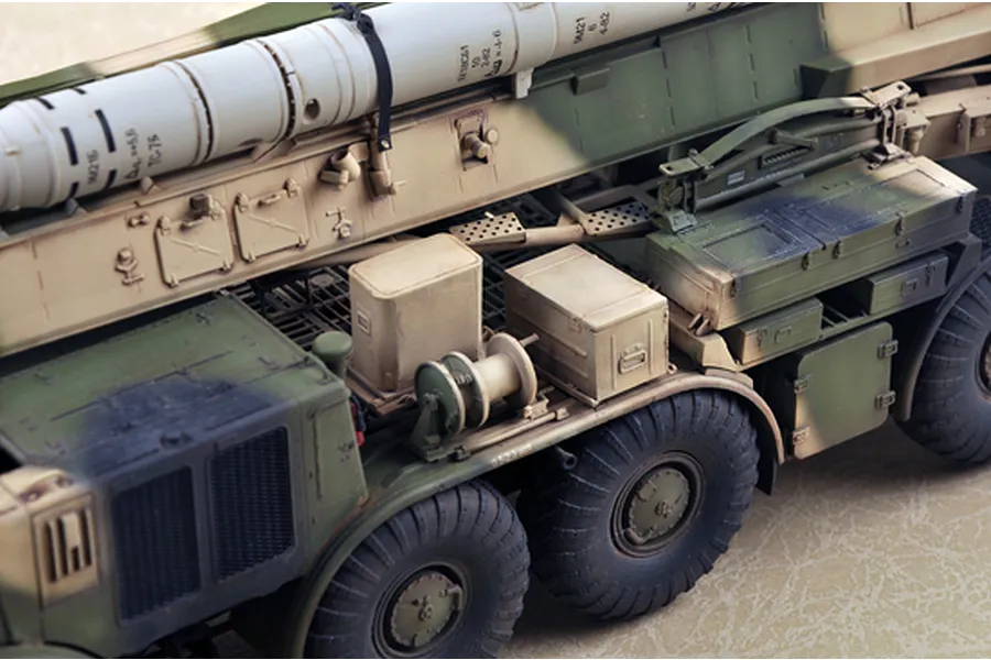 A detailed scale model of a Russian 9P113 TEL military truck with a 9M21 missile, showing side chassis details, wheels, and storage boxes.