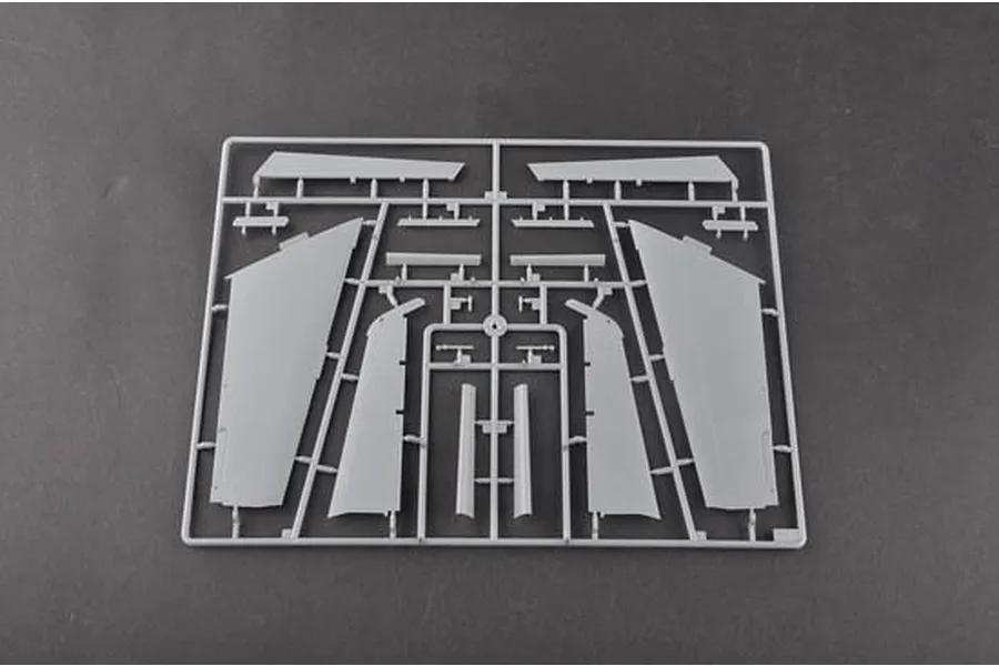 A grey plastic model kit sprue containing aircraft wing and control surface components on a dark background.