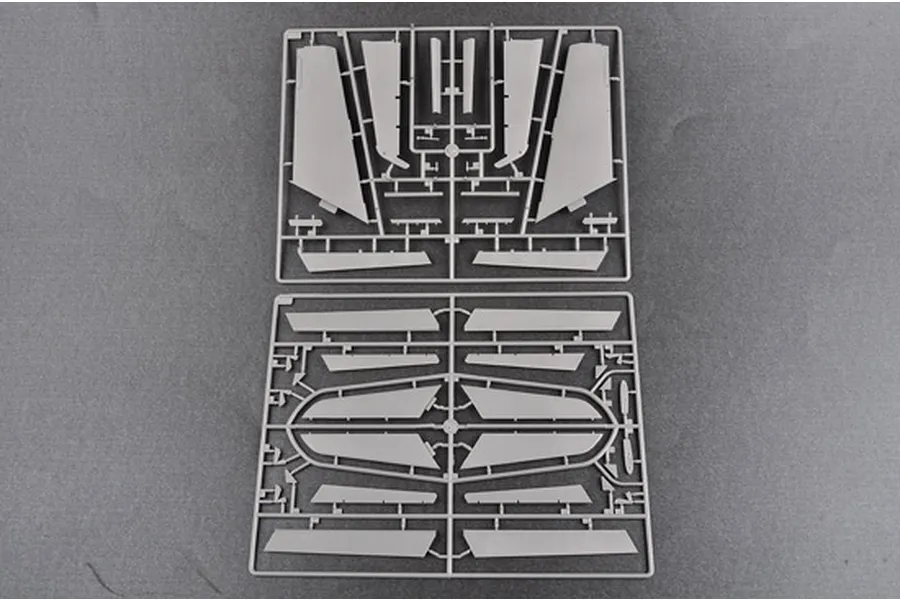 Two grey plastic model kit sprues containing various aircraft wing and control surface components laid out on a flat grey surface.