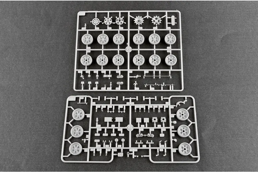 Two grey plastic model kit sprues containing various tank wheels and small mechanical parts on a dark grey background.