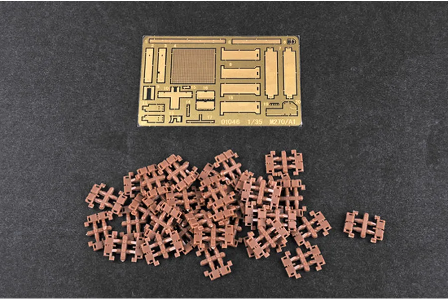 A photo-etched brass fret and a pile of small brown plastic track links for a 1/35 scale model kit.