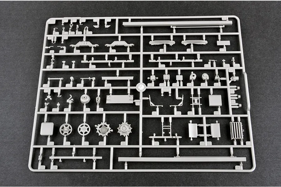 A grey plastic sprue containing various unpainted model kit parts for a 1/35 scale military vehicle, viewed from directly above on a dark background.