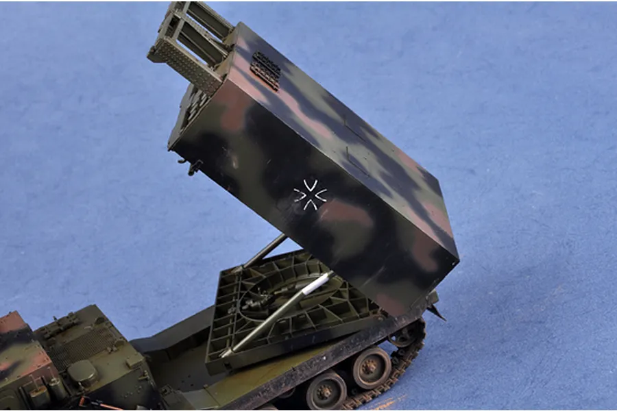 A 1/35 scale plastic model of a MARS rocket launcher vehicle with its launcher pod elevated, featuring a camouflage paint scheme and German military cross.