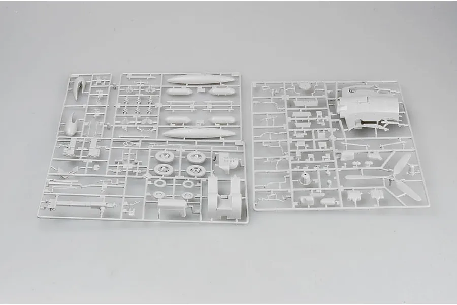 Two grey plastic model kit sprues containing various aircraft parts like fuselage sections, wheels, and propeller blades on a plain background.