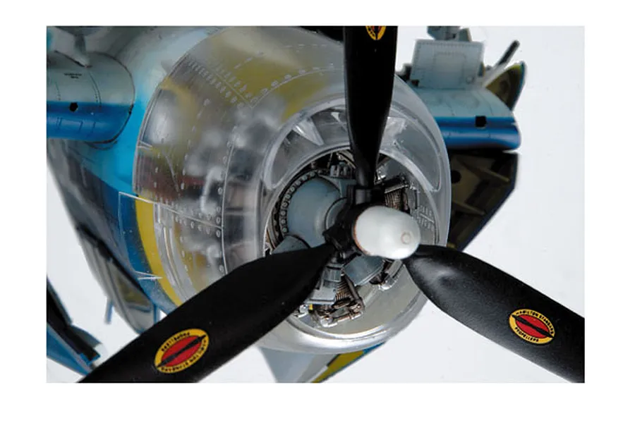 Close-up of a 1/32 scale model aircraft engine with a clear plastic cowling, showing the propeller and internal engine detail.