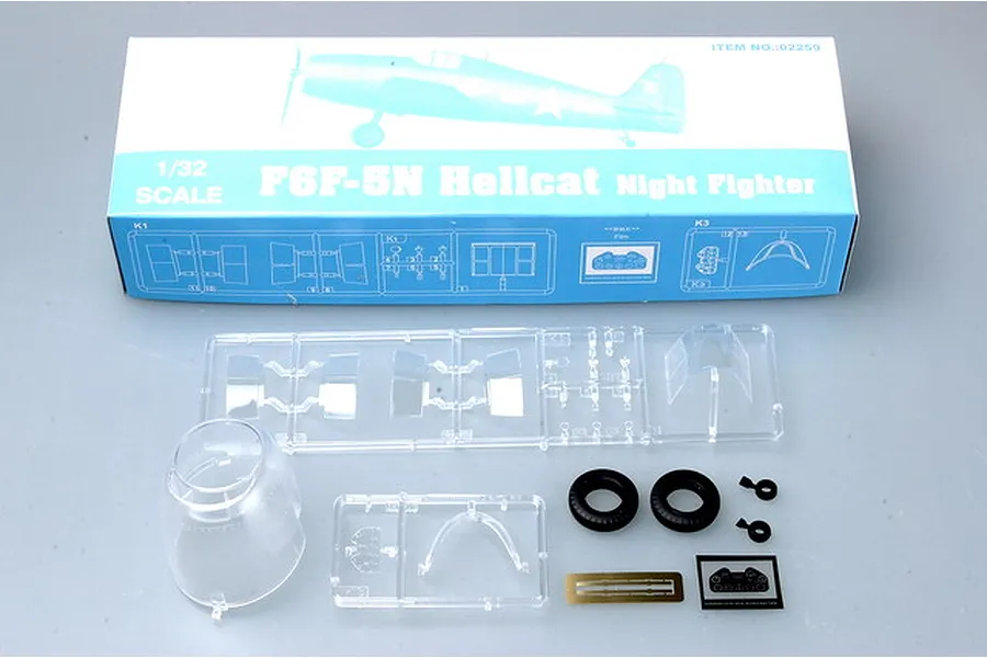 Trumpeter 1/32 scale F6F-5N Hellcat Night Fighter model kit box with clear plastic parts, rubber tires, and photo-etched details laid out in front.