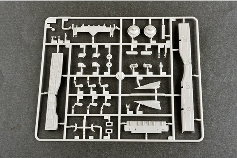 A grey plastic model kit sprue containing various tank parts, including side skirts and suspension components, on a dark grey background.