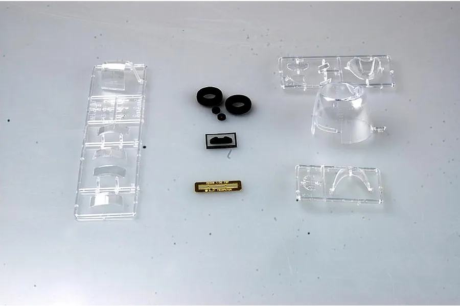 Clear plastic model kit sprues, black rubber tires, and a small photo-etched metal part for a 1/32 scale aircraft model.
