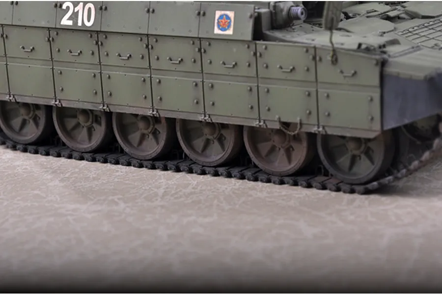 Close-up of the side hull and tracks of a 1/35 scale plastic model of a BMPT Terminator tank, showing olive green armor panels and the number 210.