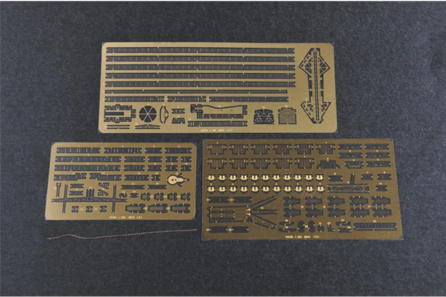 Three photo-etched brass detail sheets and a small length of metal chain for a 1/350 scale model kit, laid out on a dark grey surface.