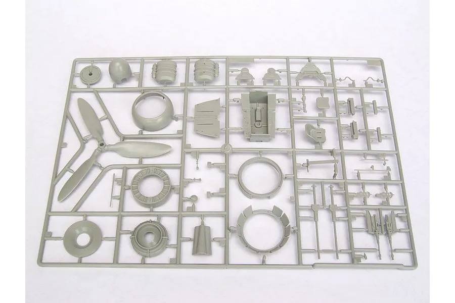 A grey plastic sprue containing various model aircraft parts, including a propeller, cockpit components, and engine parts for a 1/24 scale model kit.
