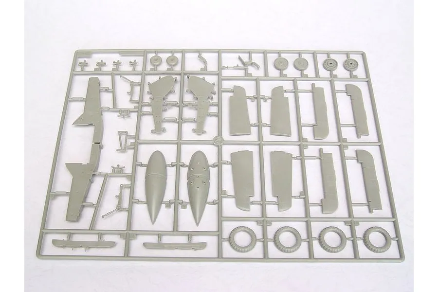 A grey plastic sprue containing various model aircraft parts, including wing sections, wheels, and fuselage components for a 1/24 scale model kit.