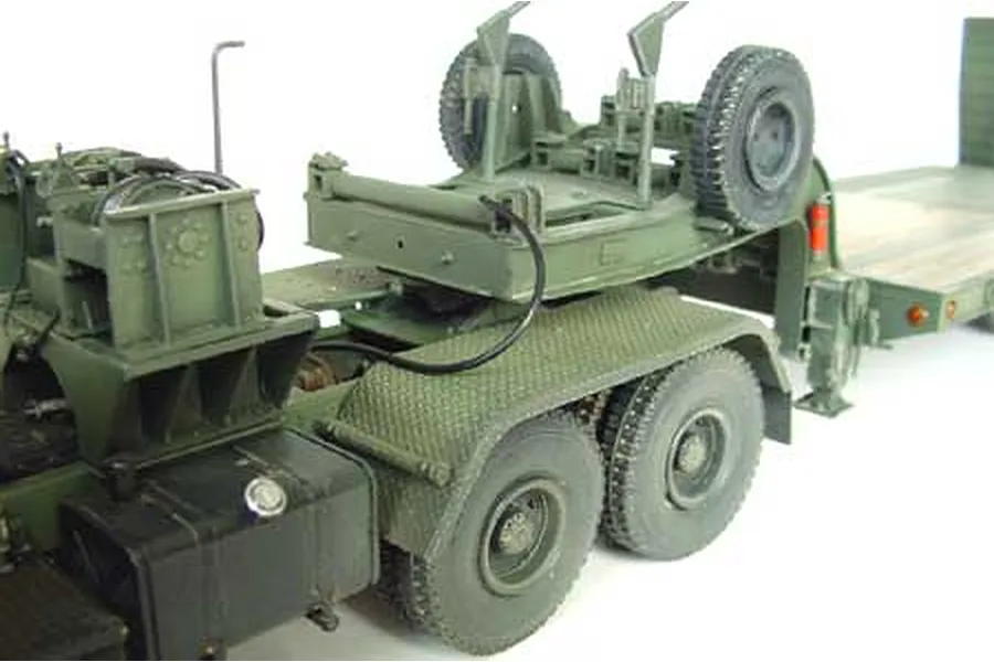A close-up view of a 1/35 scale model Chinese tank transporter truck, showing the rear chassis, wheels, and trailer hitch assembly in olive green plastic.