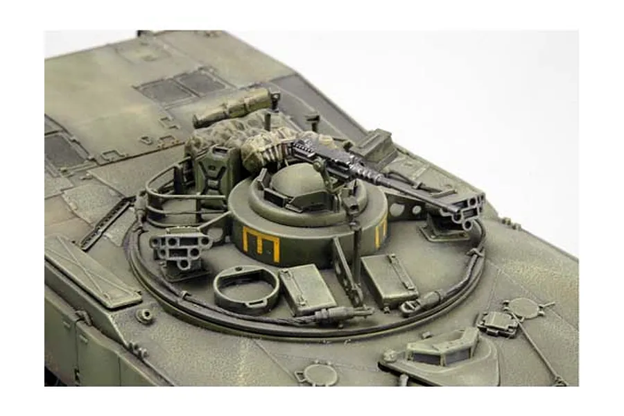Close-up of a painted 1/35 scale model tank turret with a machine gun and detailed surface features.