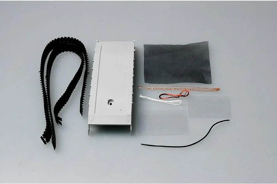 Components for a 1/35 scale model tank kit including plastic tracks, a hull piece, mesh screen, chain, wire, and decals on a grey background.