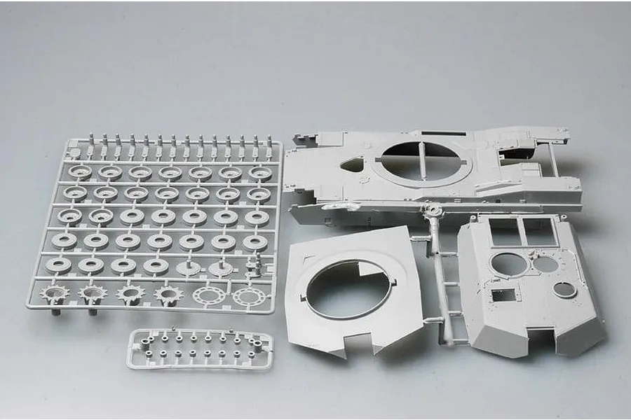 Grey plastic model kit sprues for a 1/35 scale tank, showing road wheels, hull, and turret components on a plain background.