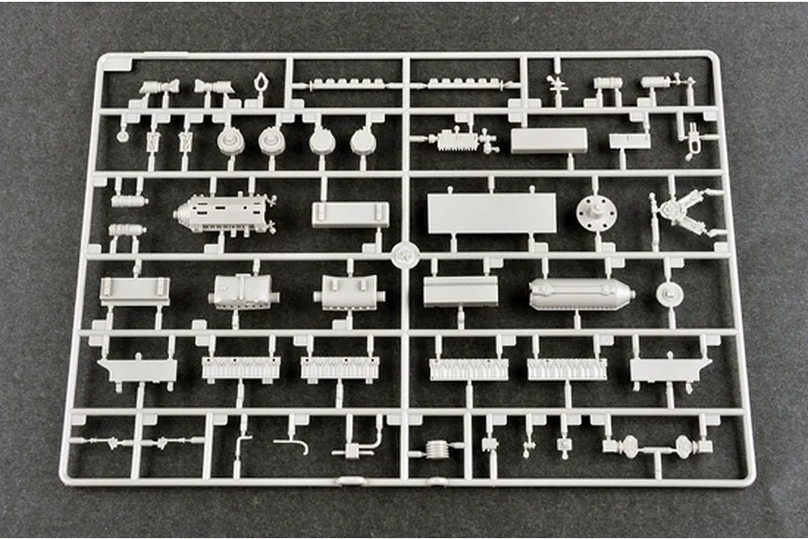 A grey plastic model kit sprue containing various small parts for a 1/35 scale military vehicle model, laid out on a dark grey surface.