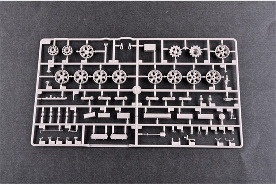 A grey plastic sprue containing various model tank road wheels, sprockets, and small mechanical parts for a 1/35 scale model kit.