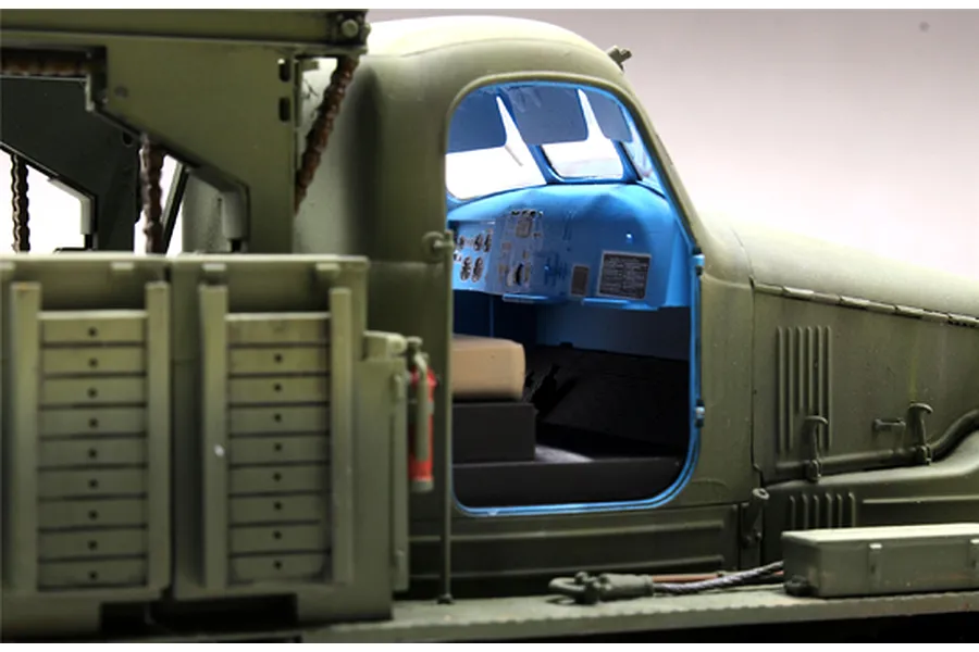 A close-up view of the cabin interior of a 1/35 scale BTM-3 trench digger model, showing the olive green exterior and a bright blue dashboard.