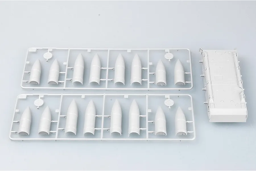 Two plastic model kit sprues containing tank shell parts and a separate tank hull section on a light grey background.