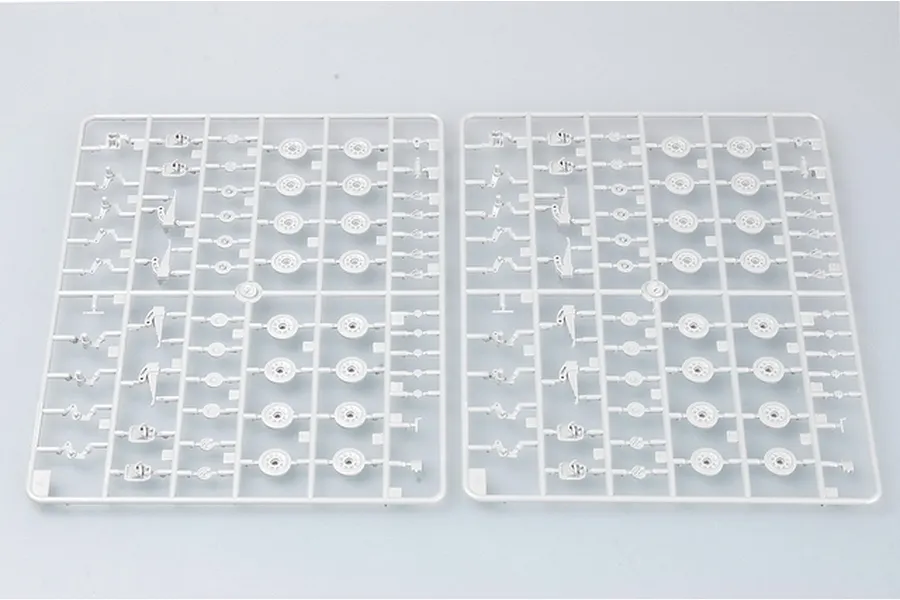 Two identical grey plastic model kit sprues containing tank wheel and suspension parts on a plain background.