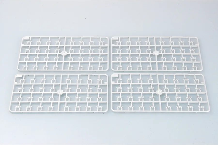 Four identical grey plastic model kit sprues containing small track link parts arranged on a light grey background.