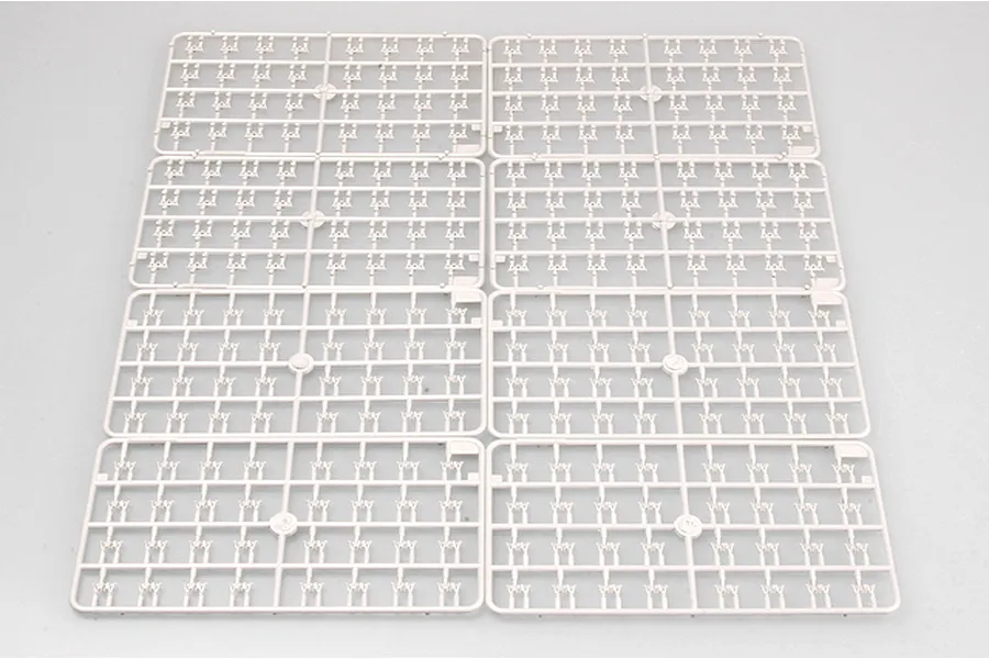 Eight identical light grey plastic model kit sprues containing numerous small track link parts arranged on a white surface.