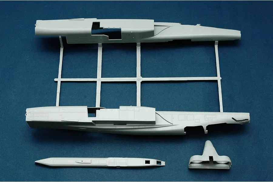 Plastic model kit parts for a Trumpeter 1/48 RA-5C Vigilante, showing fuselage halves on a sprue and separate components on a blue background.