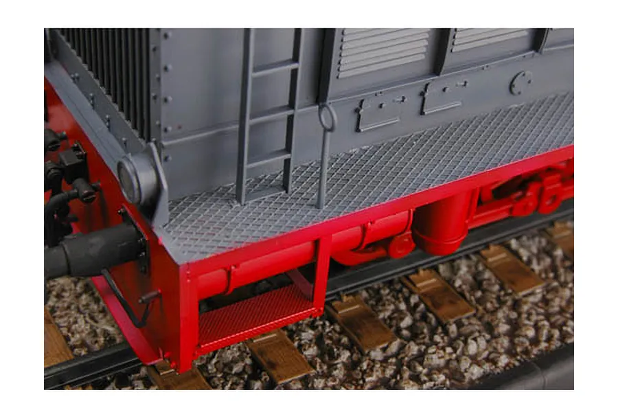 Close-up of a grey and red model locomotive on a track, showing the ladder, walkway, and chassis details.