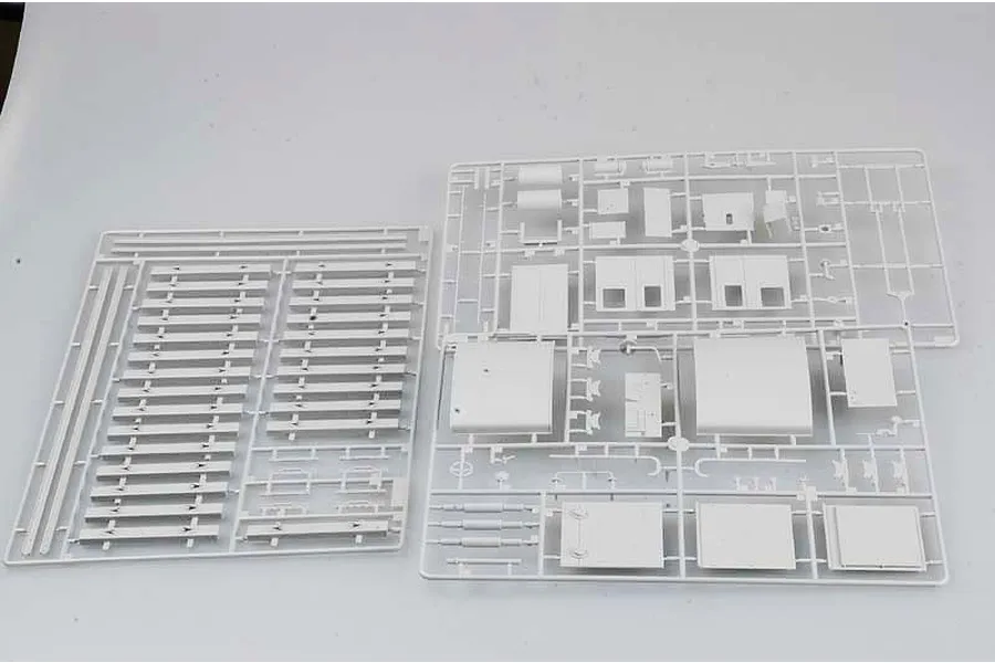 Two white plastic model kit sprues containing various locomotive parts and track sections laid out on a white surface.
