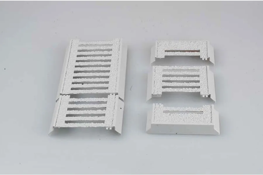 Several white plastic model kit parts with textured surfaces arranged on a plain background.