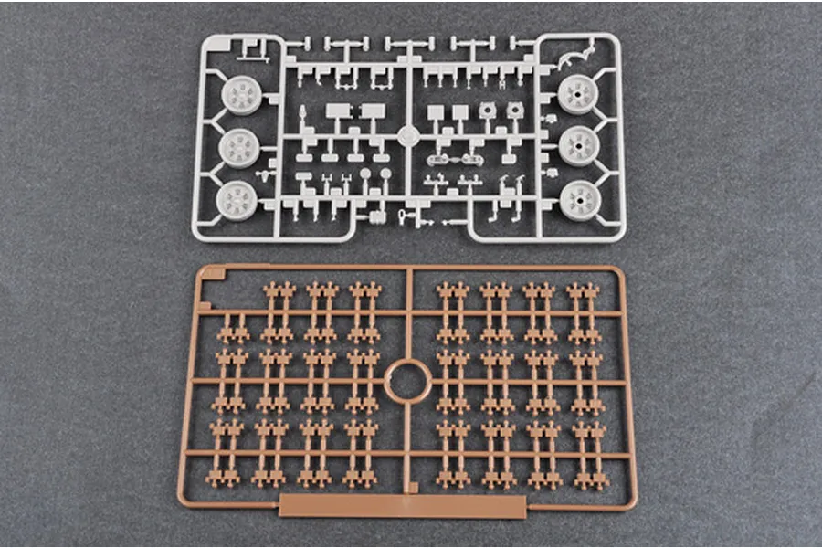 Two plastic model kit sprues on a grey background, one grey with tank parts and one brown with track links.