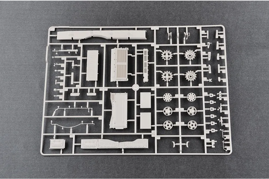 A grey plastic sprue containing various unpainted model tank parts, including wheels, hull sections, and small mechanical components.