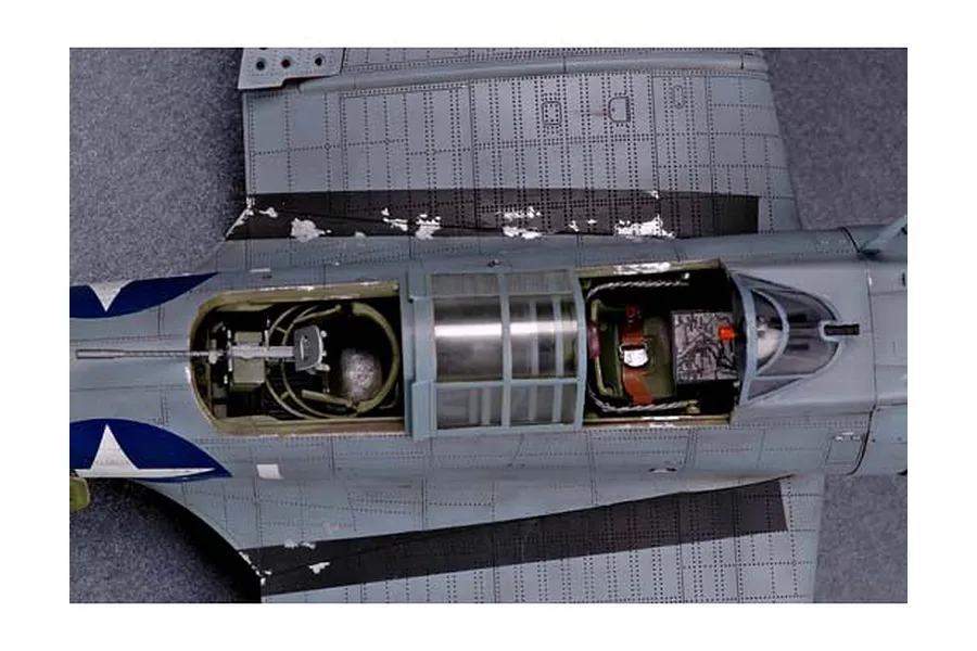 Top-down view of a detailed scale model aircraft cockpit and wing section, showing weathered paint, gunner station, and pilot seat.