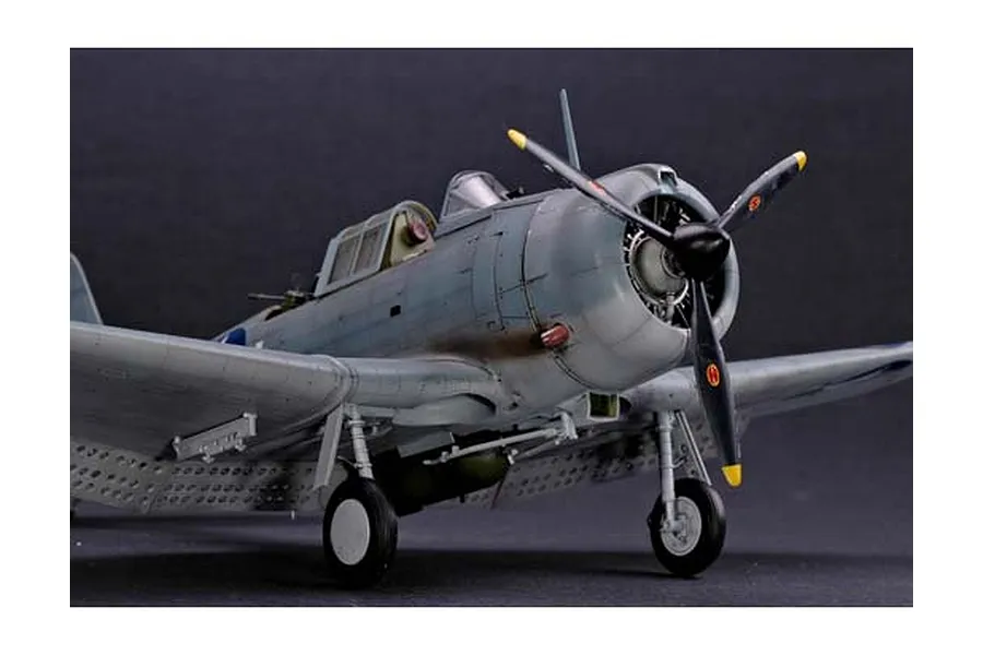 A detailed scale model of a U.S. Navy SBD Dauntless dive bomber, featuring weathered grey paint, a three-blade propeller, and landing gear.