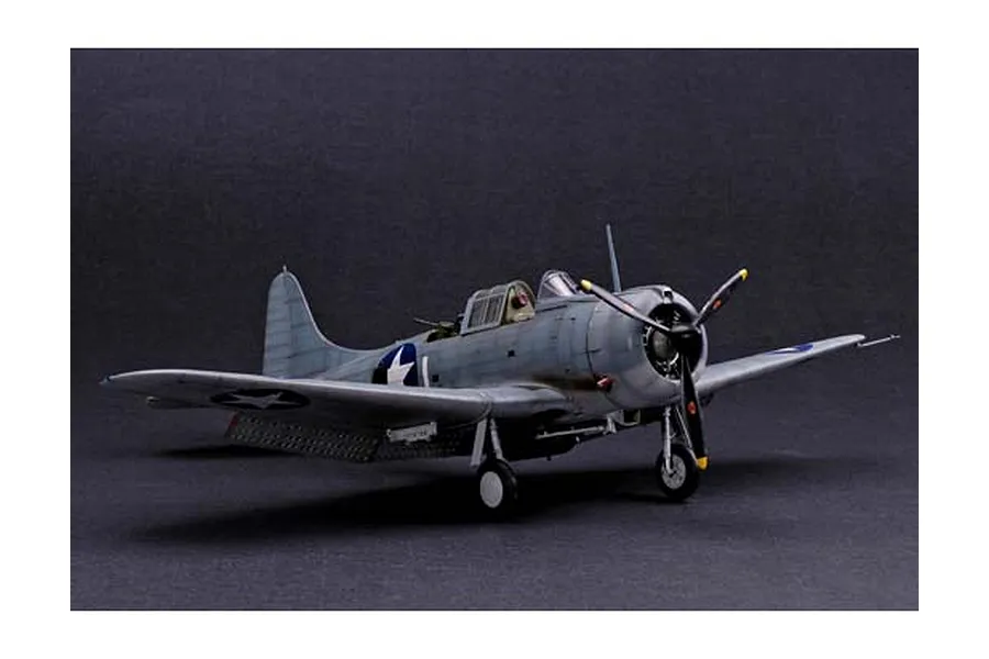A 1/32 scale plastic model of a US Navy SBD Dauntless dive bomber, painted in grey camouflage with US insignia, displayed against a dark background.