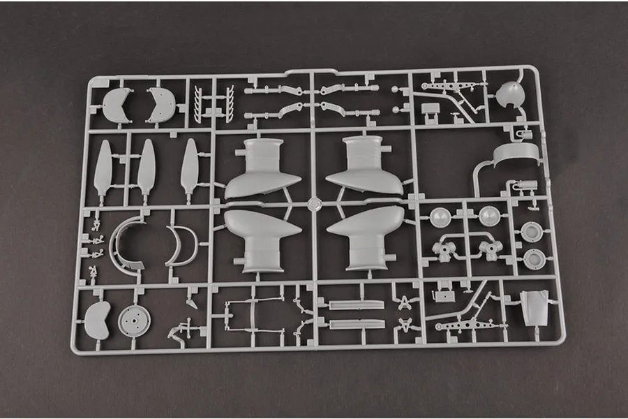 A grey plastic sprue containing various model aircraft parts, including propeller blades, engine components, and landing gear struts.