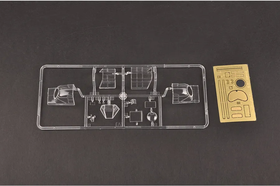 A clear plastic sprue containing aircraft canopy parts and a small photo-etched metal sheet for a 1/32 scale model kit.