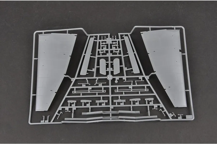 A grey plastic sprue from a model kit containing aircraft wing sections and various small structural components.