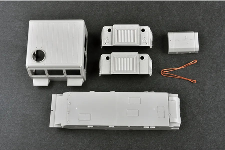 Unassembled grey plastic model kit parts for the Trumpeter 1/35 Russian AT-S Artillery Tractor, including the main chassis, cab, and engine components.