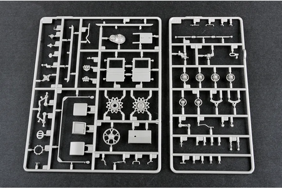 Two grey plastic model kit sprues containing various vehicle parts laid out on a dark surface.