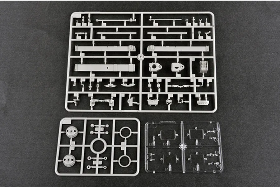 Three plastic model kit sprues for a 1/35 scale military vehicle, including two grey plastic frames and one clear plastic frame on a dark background.