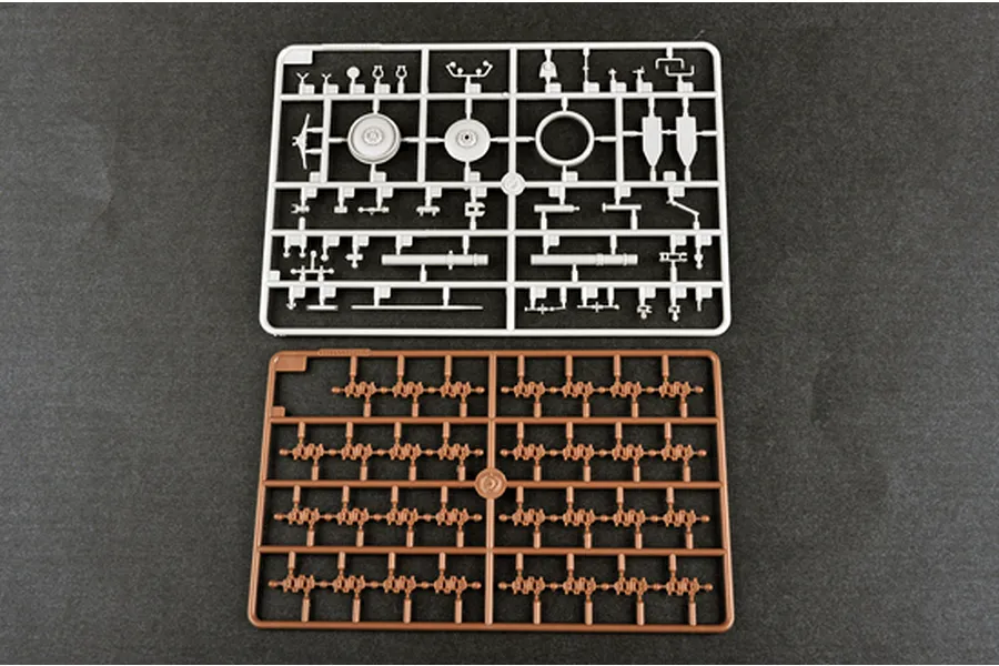 Two plastic model kit sprues from a Trumpeter 1/35 scale military vehicle kit, one grey and one brown, laid out on a dark grey surface.