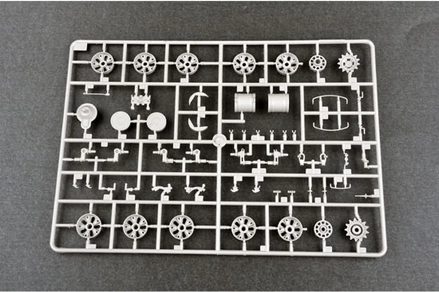 A grey plastic sprue containing various tank model parts, including road wheels, sprockets, and suspension components for a 1/35 scale model kit.