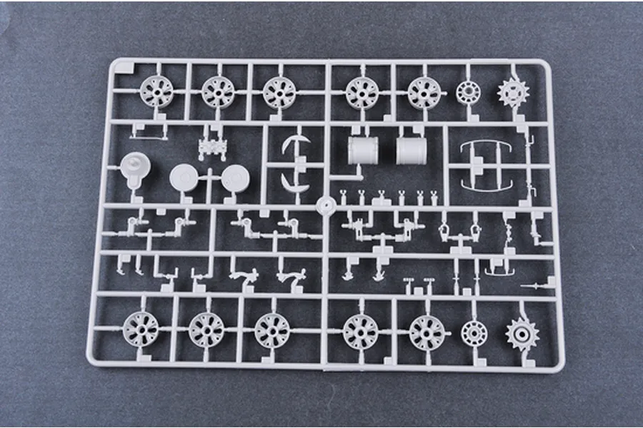 A grey plastic model kit sprue containing various tank wheels, suspension parts, and small components for a 1/35 scale model.